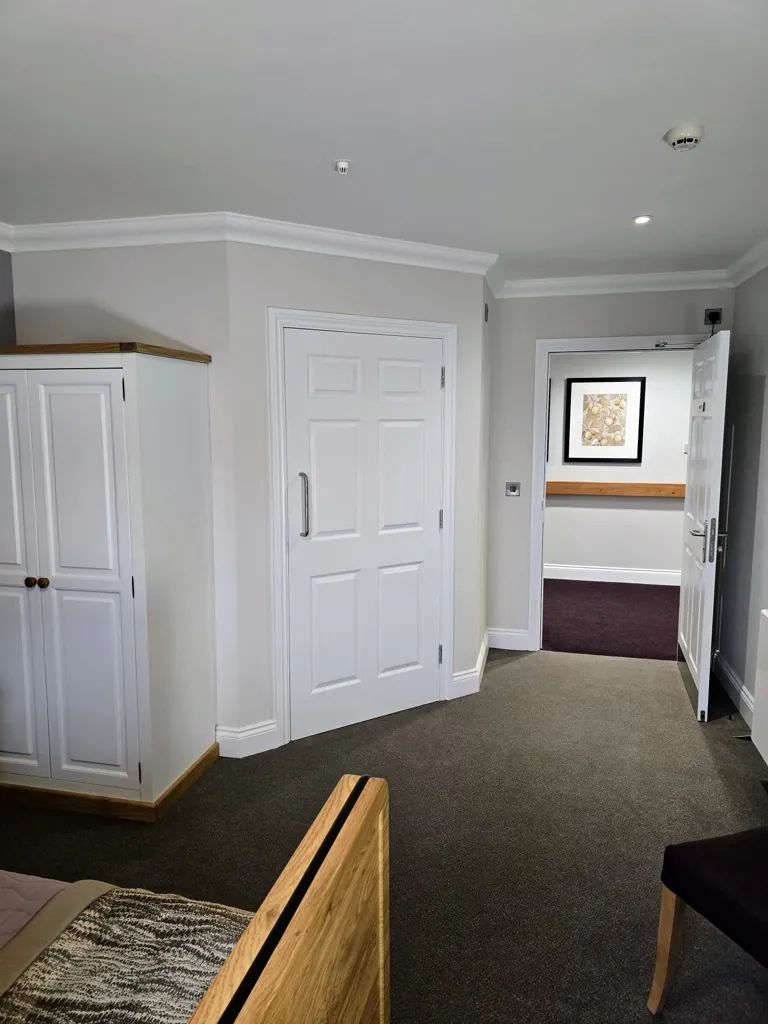 Bedroom interior with white door, built-in wardrobe and carpeted flooring