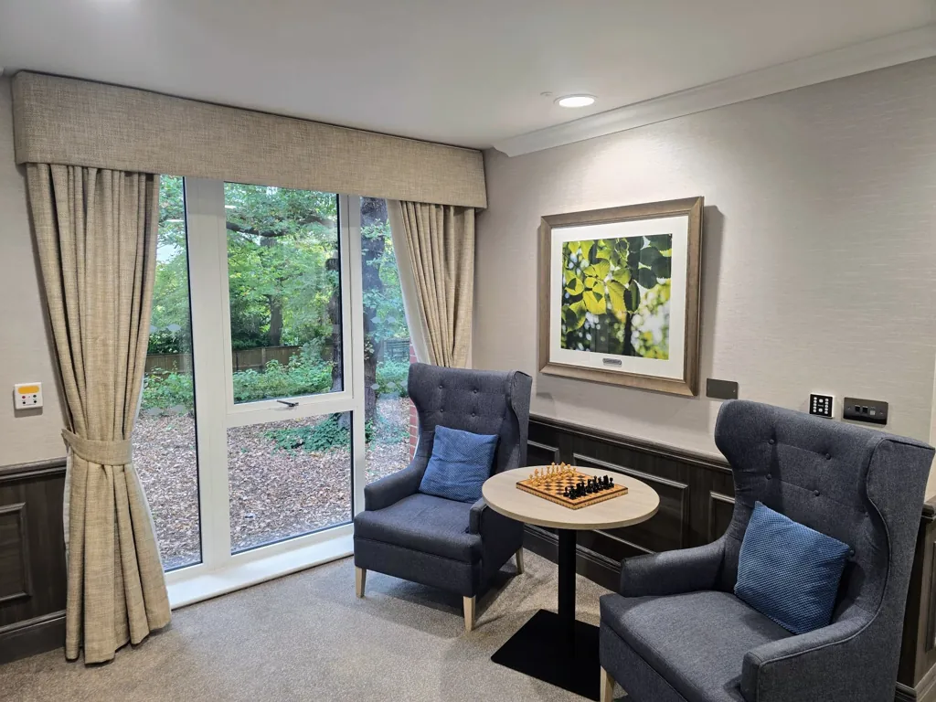 Seating area with two armchairs and small table by window overlooking garden