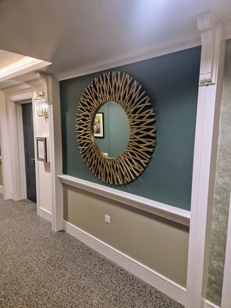 Decorative wall feature with large round mirror on coloured panelled wall