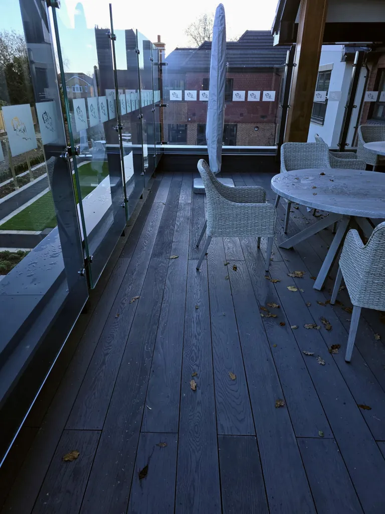 Balcony walkway with composite decking, glass railing and outdoor seating overlooking courtyard