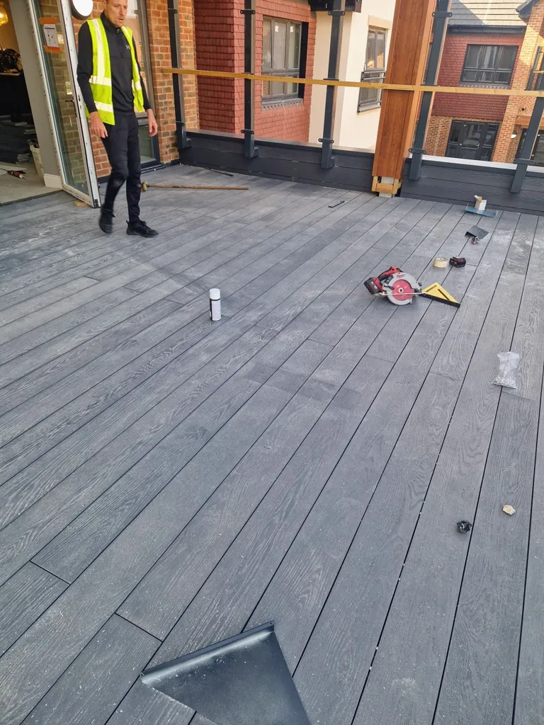 Installation work in progress on decking area with tools and worker on site