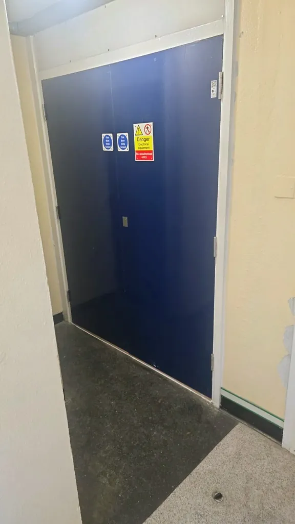 Single blue fire door with safety signage in a residential hallway