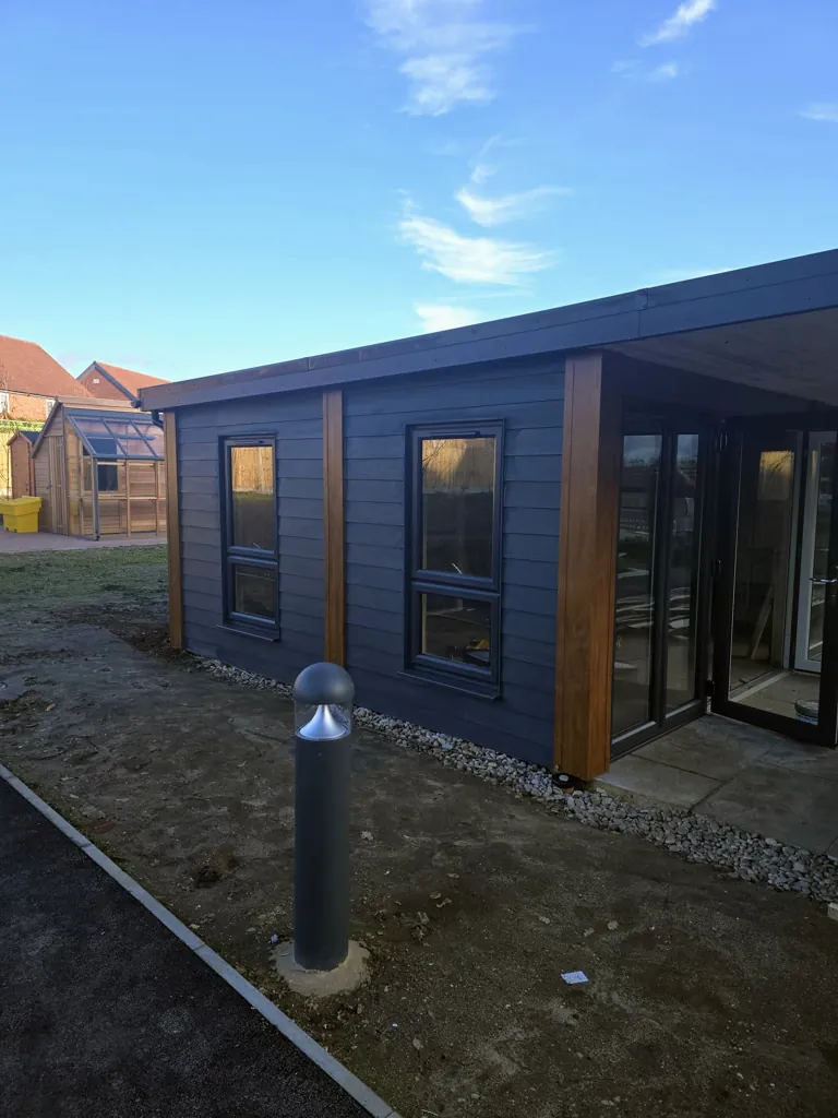 Modern garden room structure with cladding, windows and sliding glass doors in outdoor setting