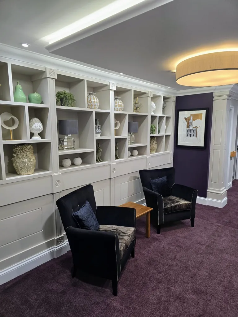 Seating area with two armchairs and wall-mounted shelving displaying decorative items