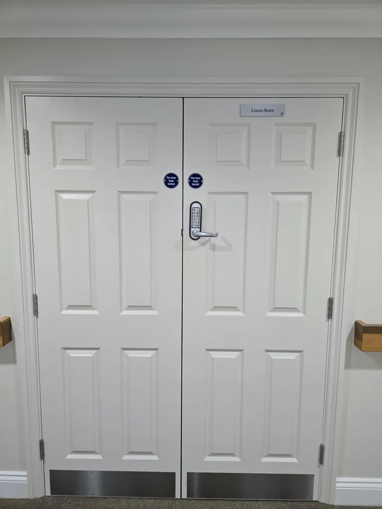 White double doors with central access control handle and metal kick plates