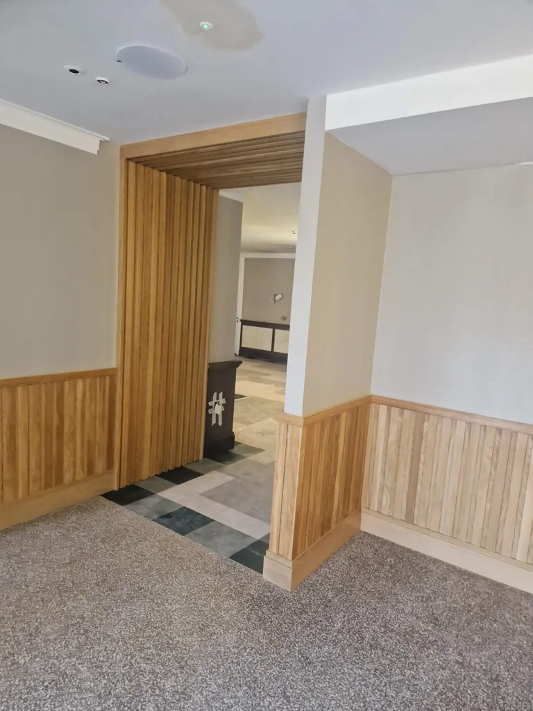 Interior opening with timber slatted partition and wall panelling leading to tiled area
